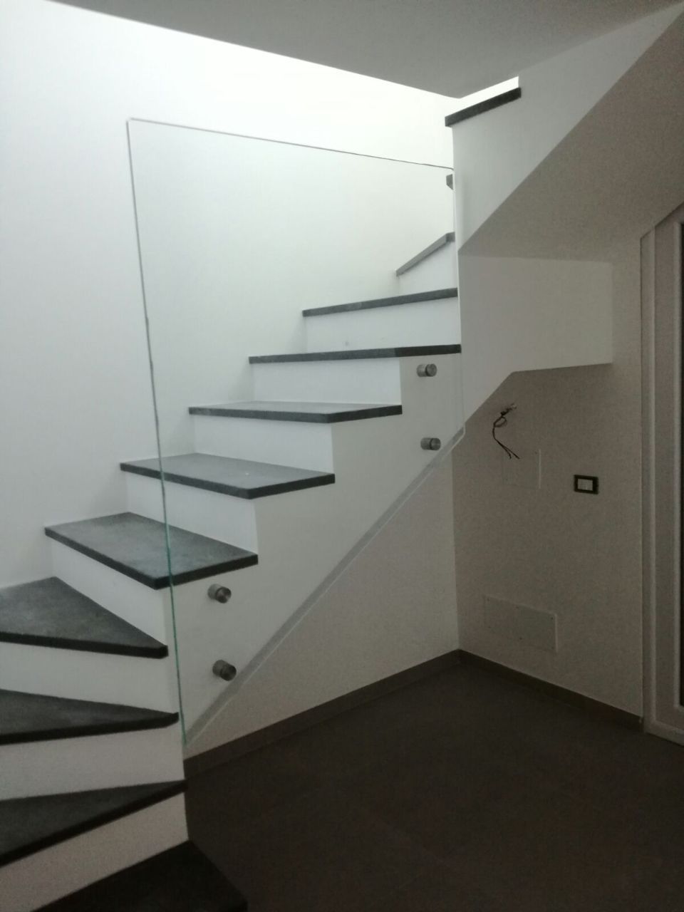 Scala moderna bianca con gradini scuri in un corridoio interno minimalista
