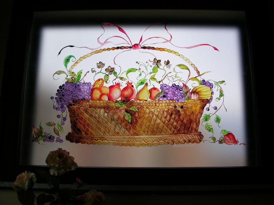 Cesto decorativo con frutta e fiori assortiti e nastri colorati su sfondo bianco.