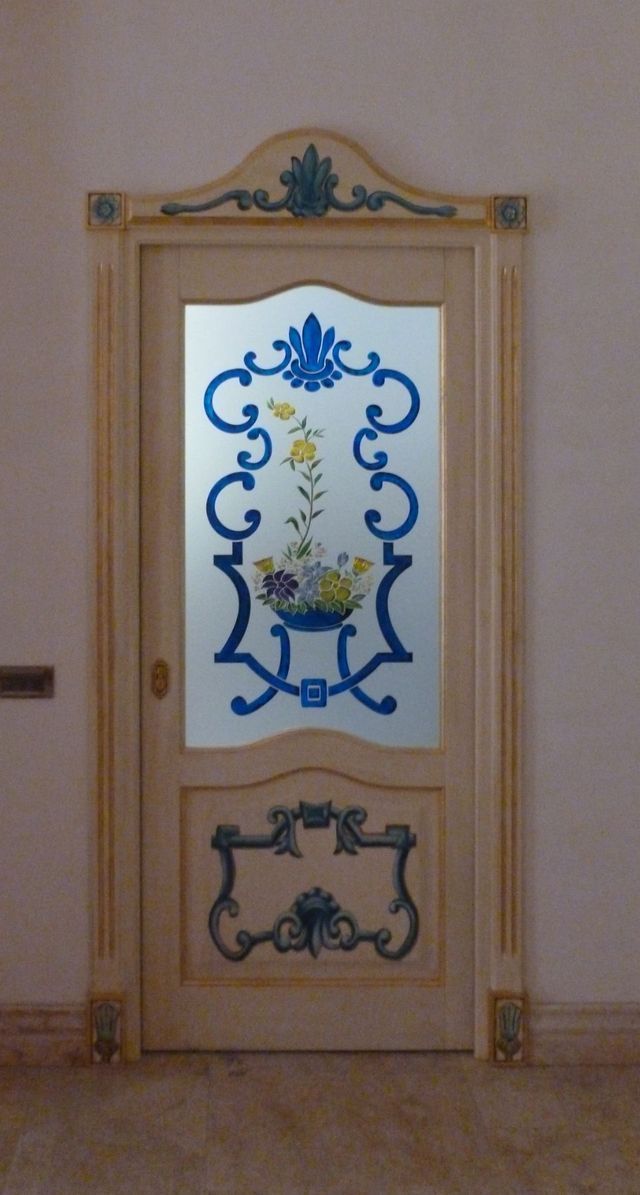 Porta decorativa beige con pannelli in vetro floreali blu e oro in un corridoio