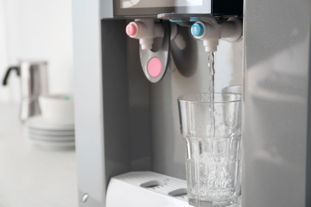 Water Cooler Dispensing Water Into a Glass, in a Kitchen Setting — Port Macquarie Pure Water In Port Macquarie, NSW