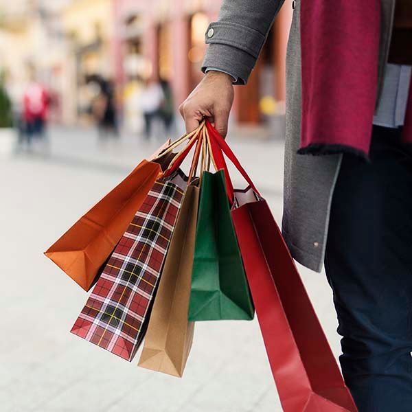 Person holding several colorful shopping bags outdoors on a city street