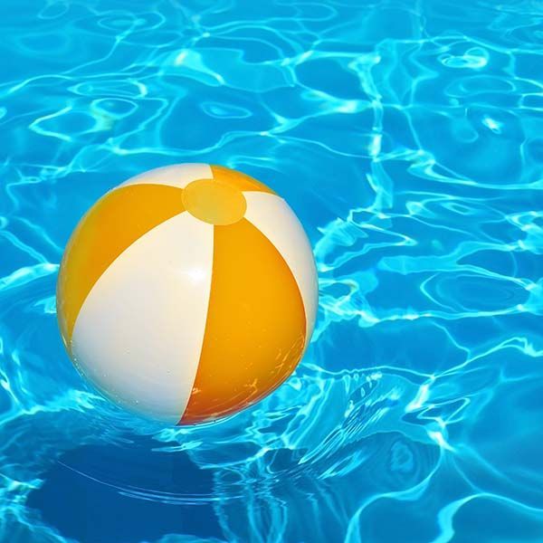 Yellow and white beach ball floating in bright blue pool water