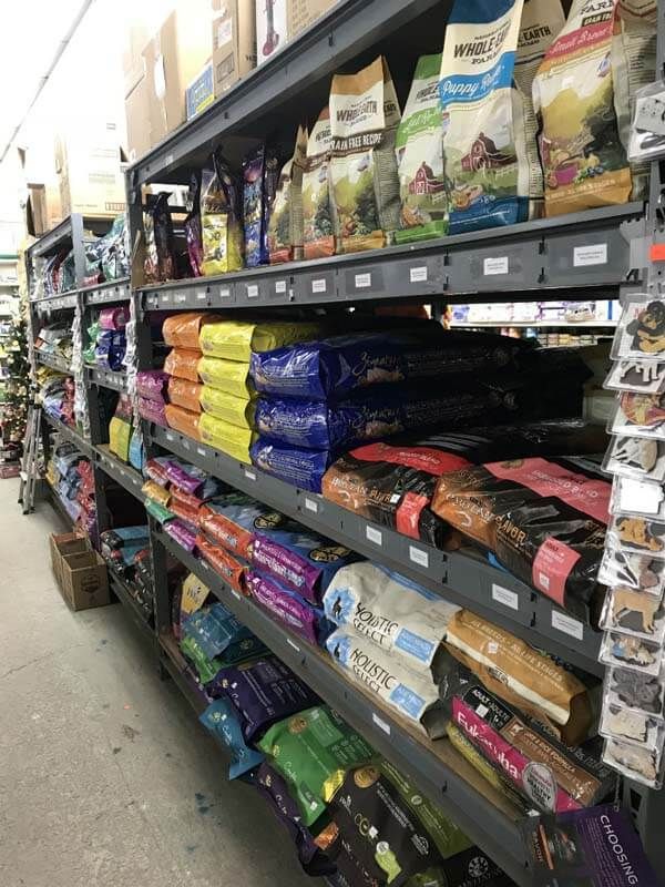 Pet store aisle with shelves of colorful pet food bags stacked neatly on both sides
