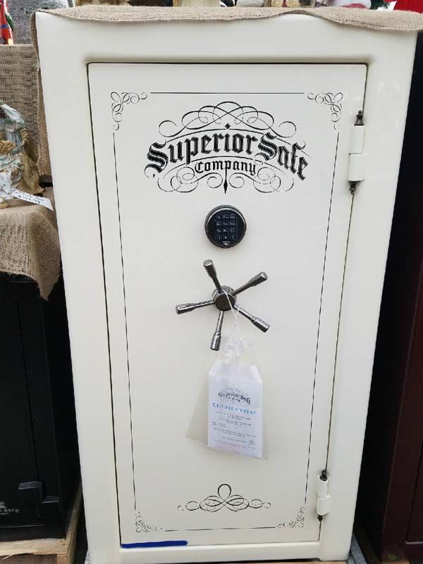 White vintage safe with “Superior Safe” logo, combination lock, and hanging tag in a storage area