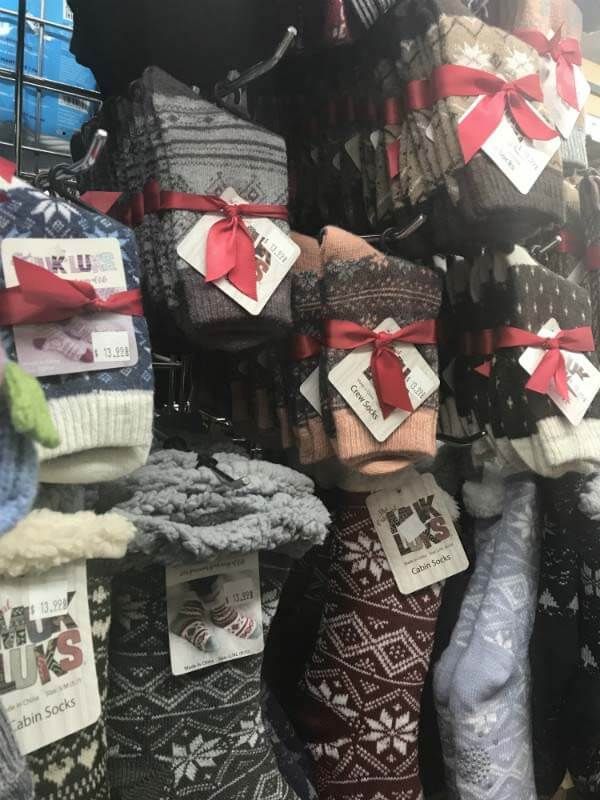 Bundles of knit socks and gloves with red ribbons hanging in a shop display
