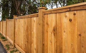 A close up of a wooden fence with trees in the background.