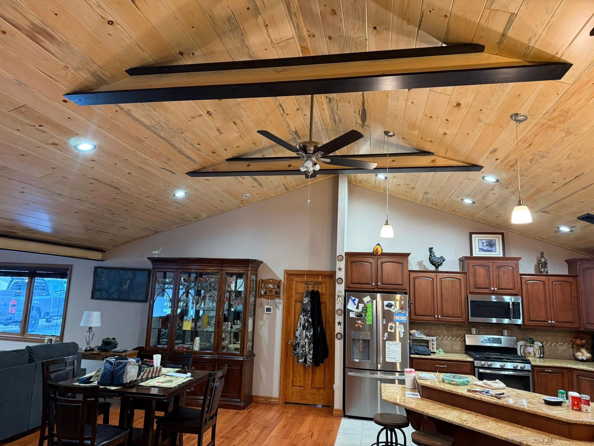 Open kitchen and dining area with wood ceiling, ceiling fans, cabinets, and island counter