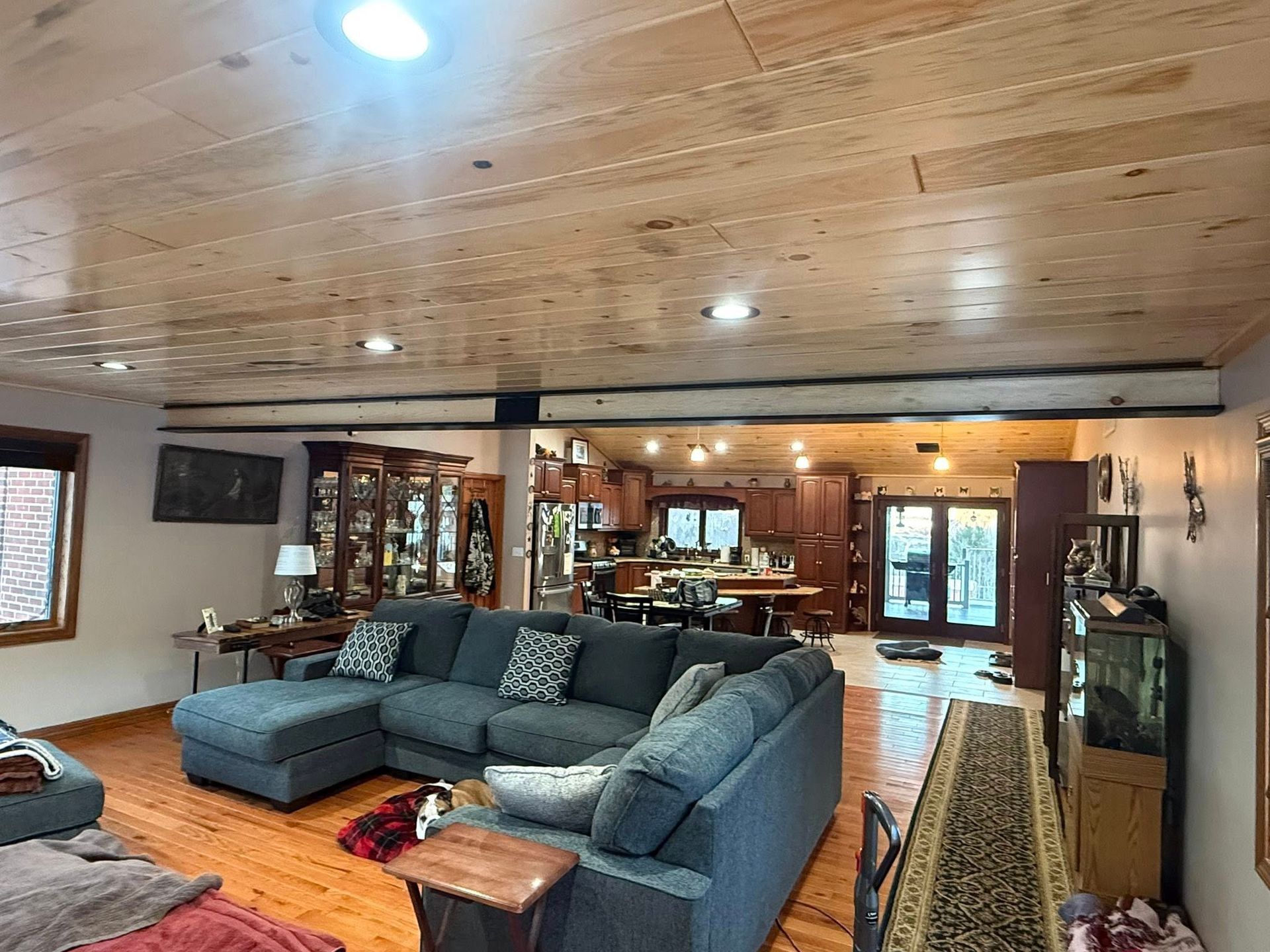 Spacious living room with gray sectional, wood ceiling, fireplace, and large windows