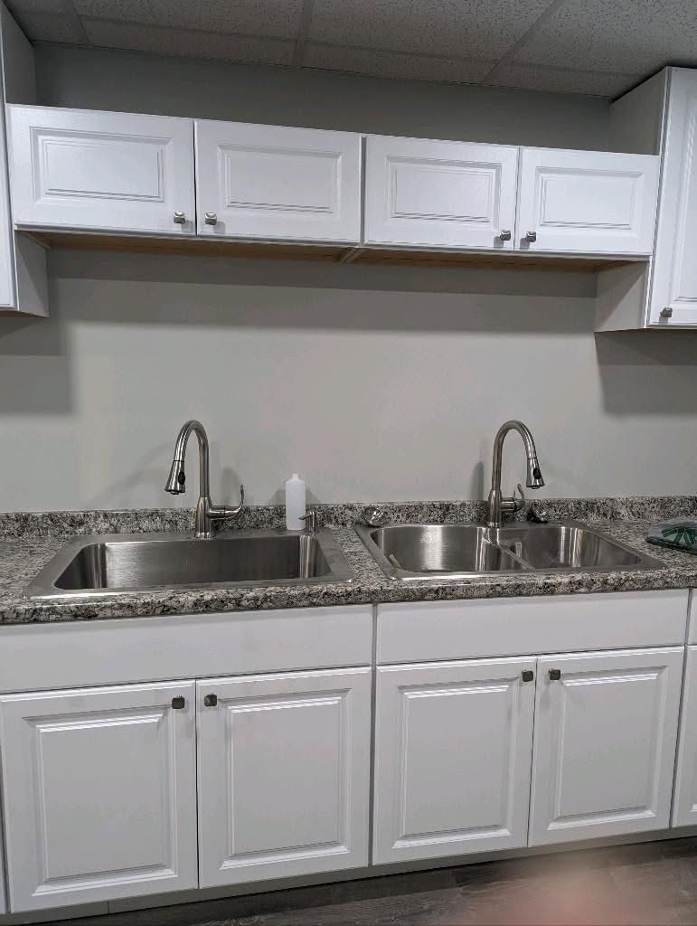 White kitchen with double sink, granite countertop, and upper and lower cabinets.