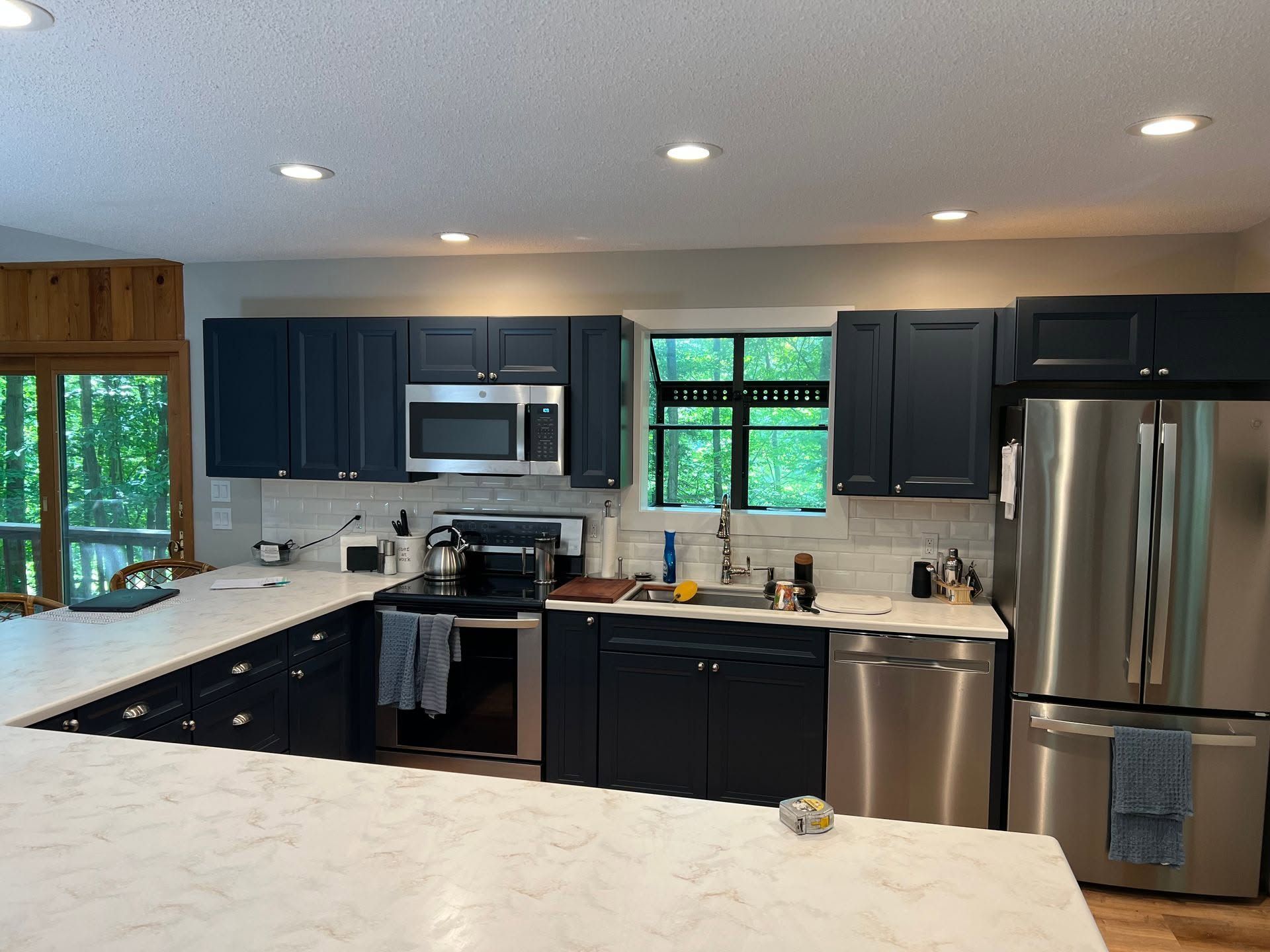 Modern kitchen with dark cabinets, stainless steel appliances, white countertops, and a large island