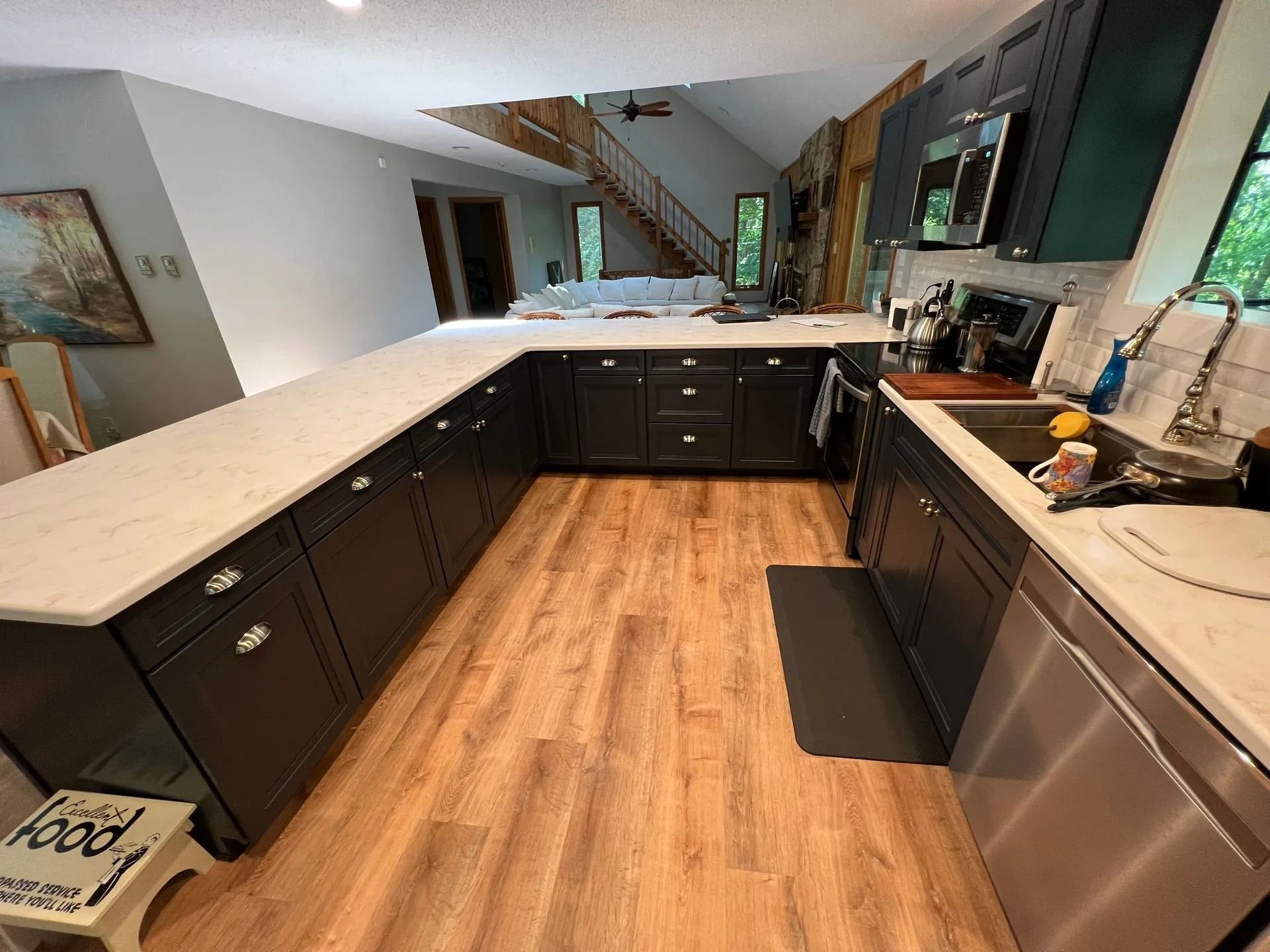 Modern kitchen with black cabinets, white countertops, and stainless steel appliances, viewed from one end