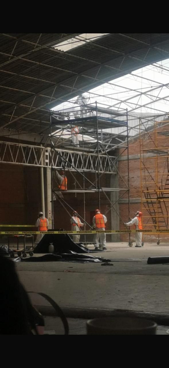 Equipo técnico con trajes de protección desmantelando techado de asbesto