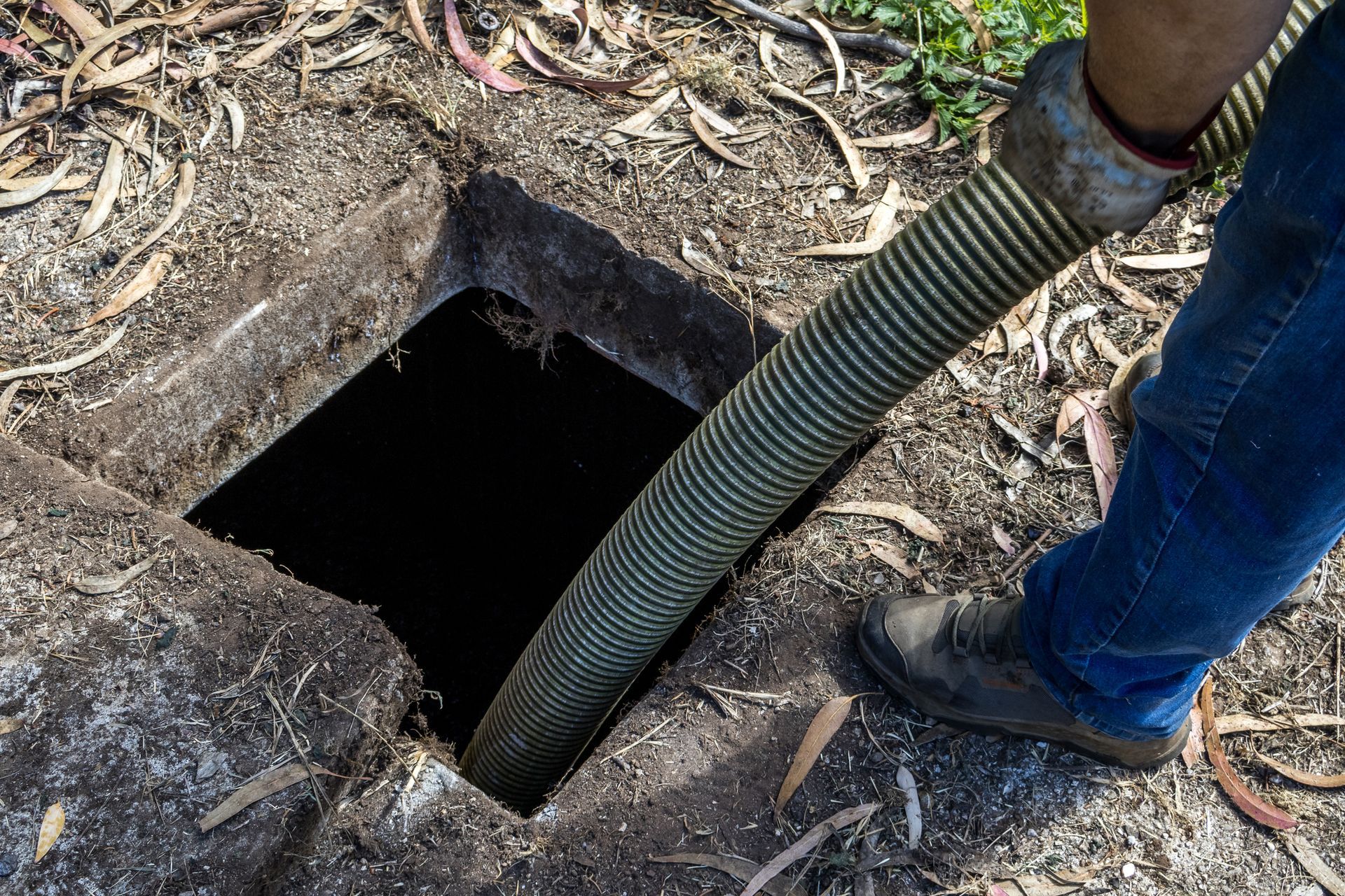 Septic tank cleaning performed by a contractor with a hose.