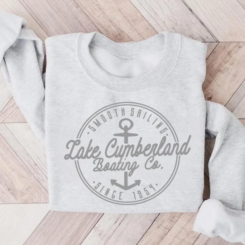 Gray sweatshirt with "Lake Cumberland Boating Co." logo, anchor, and text on wooden surface.
