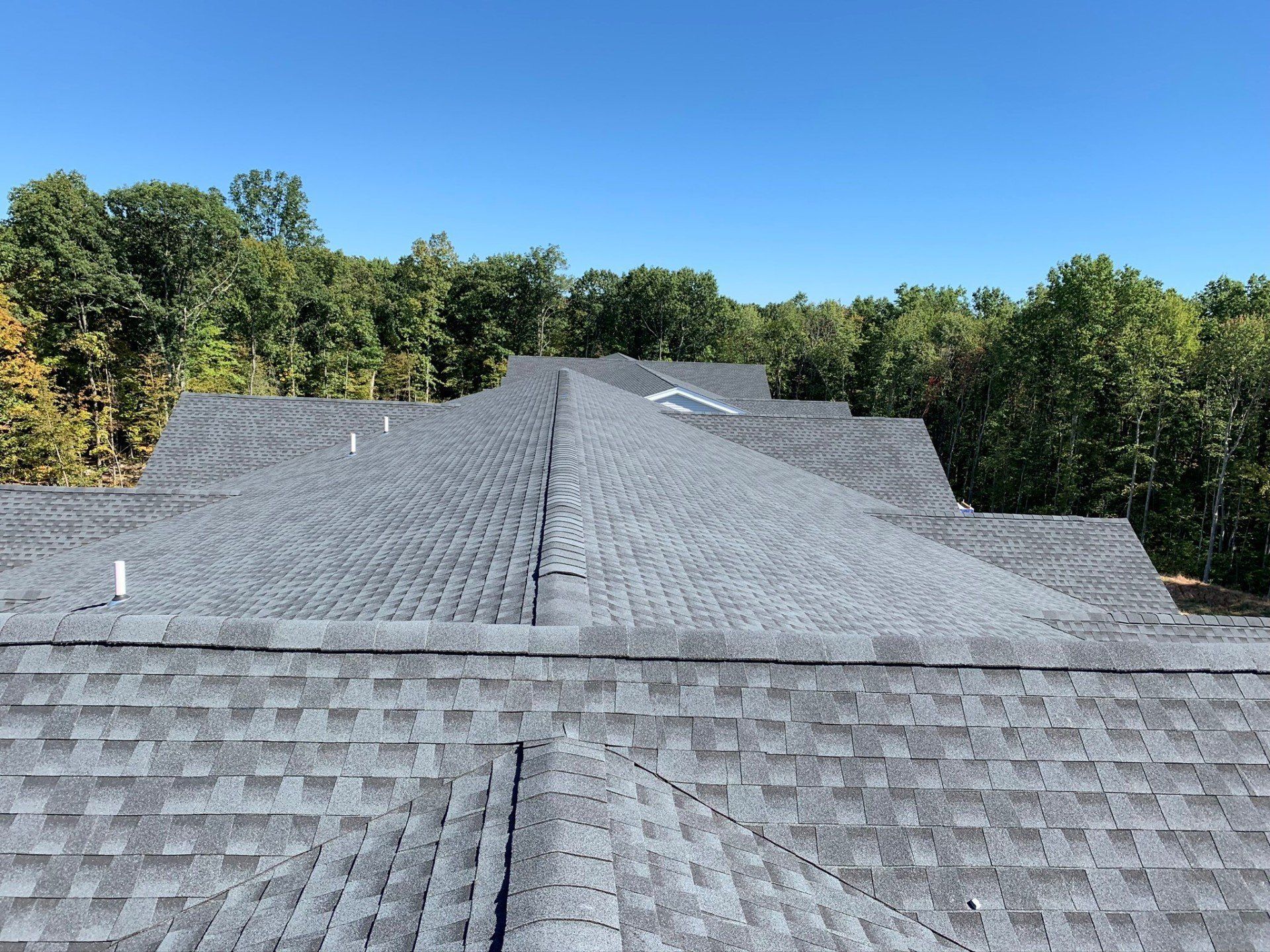 The roof of a house with a lot of shingles and trees in the background.