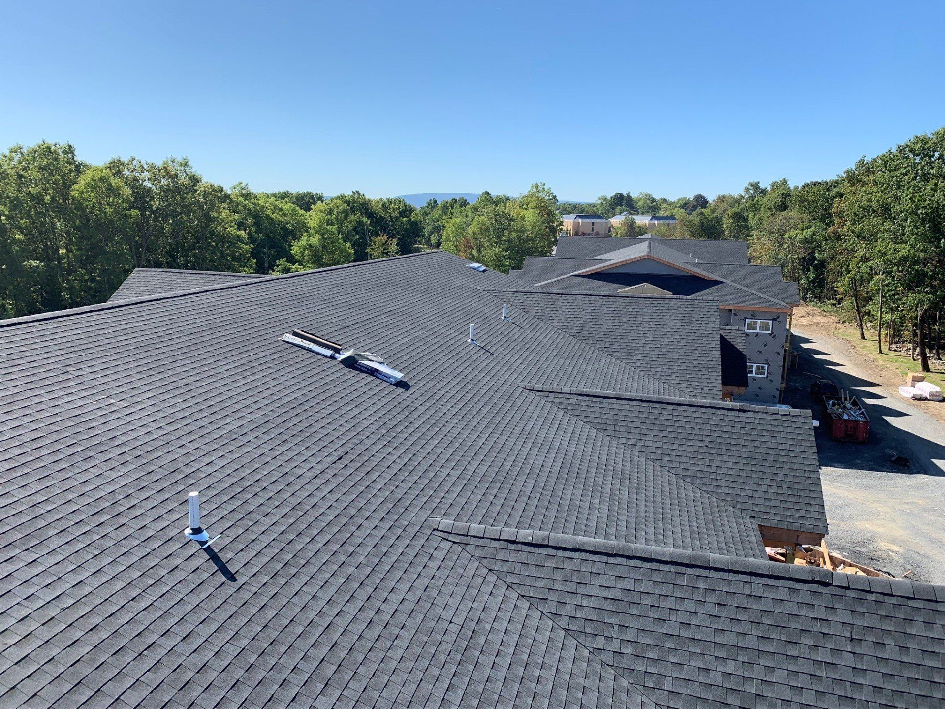An aerial view of a large building with a black roof surrounded by trees.