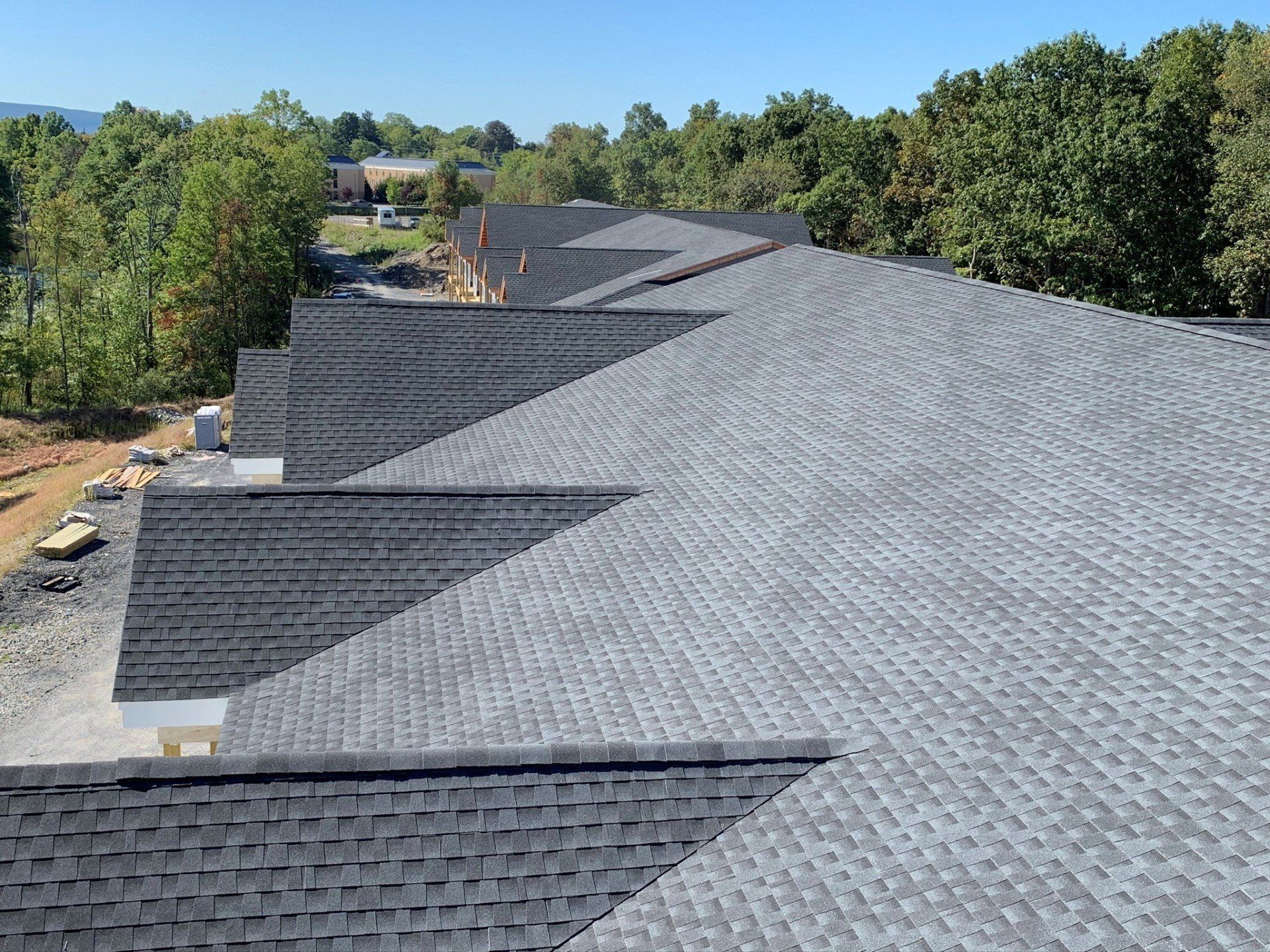 A row of houses with a gray roof and trees in the background.