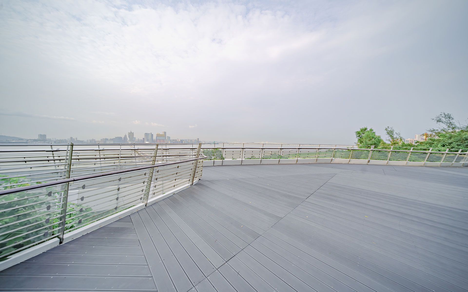 An empty deck with a railing overlooking a body of water.