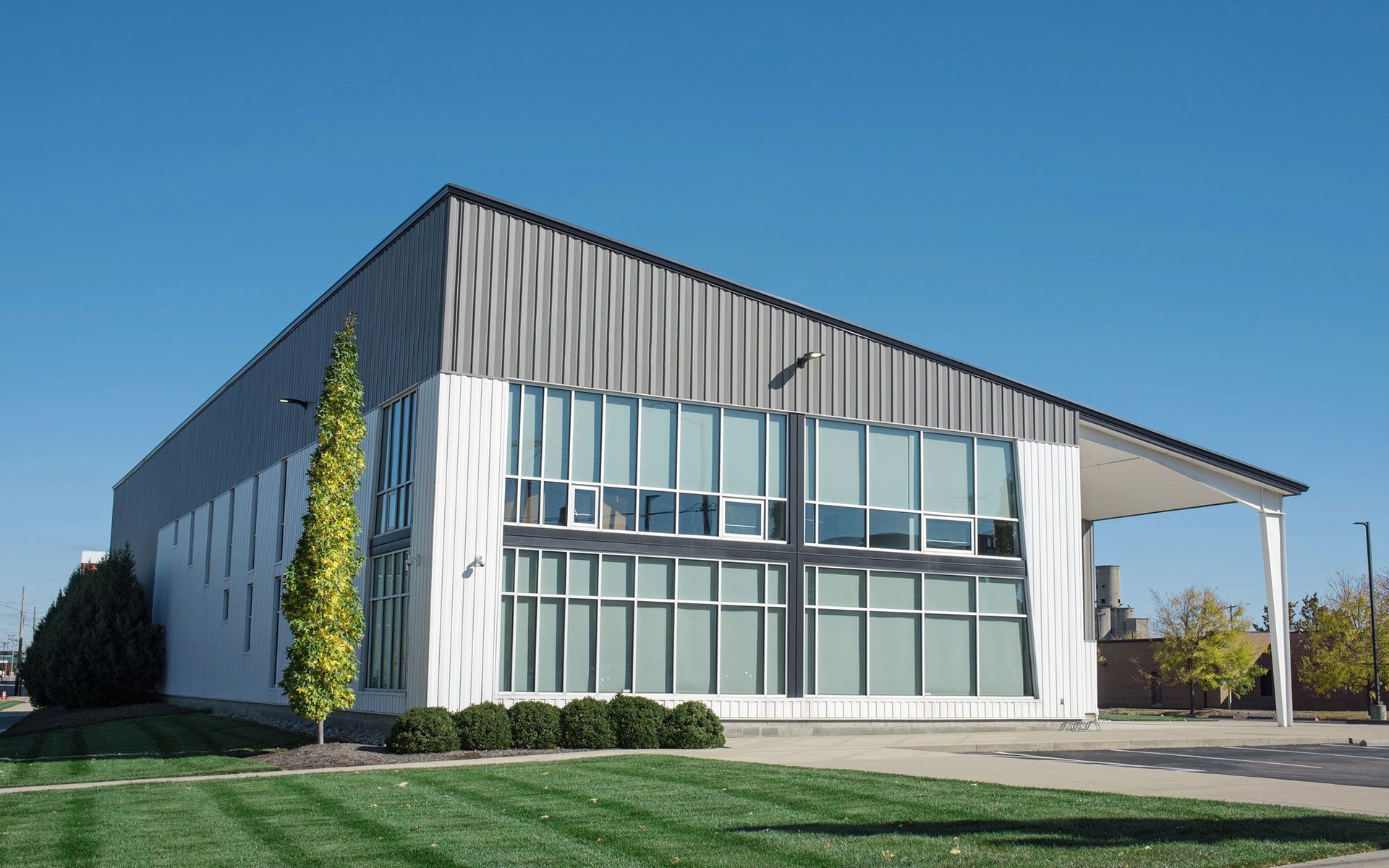 A large white building with a lot of windows is sitting on top of a lush green field.