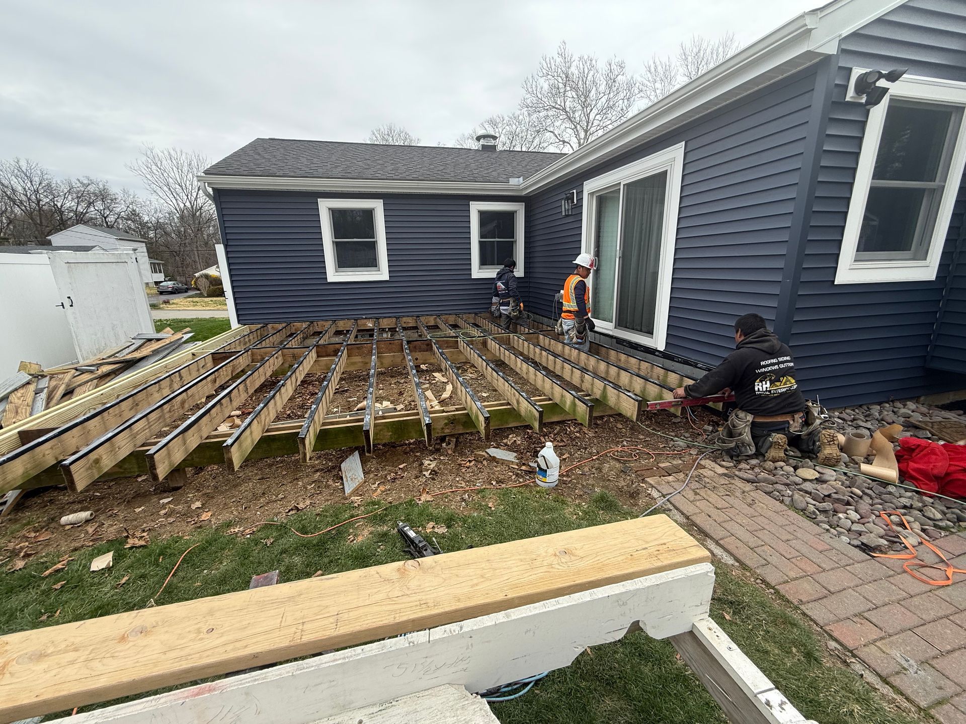 A blue house with a wooden deck being built in front of it.
