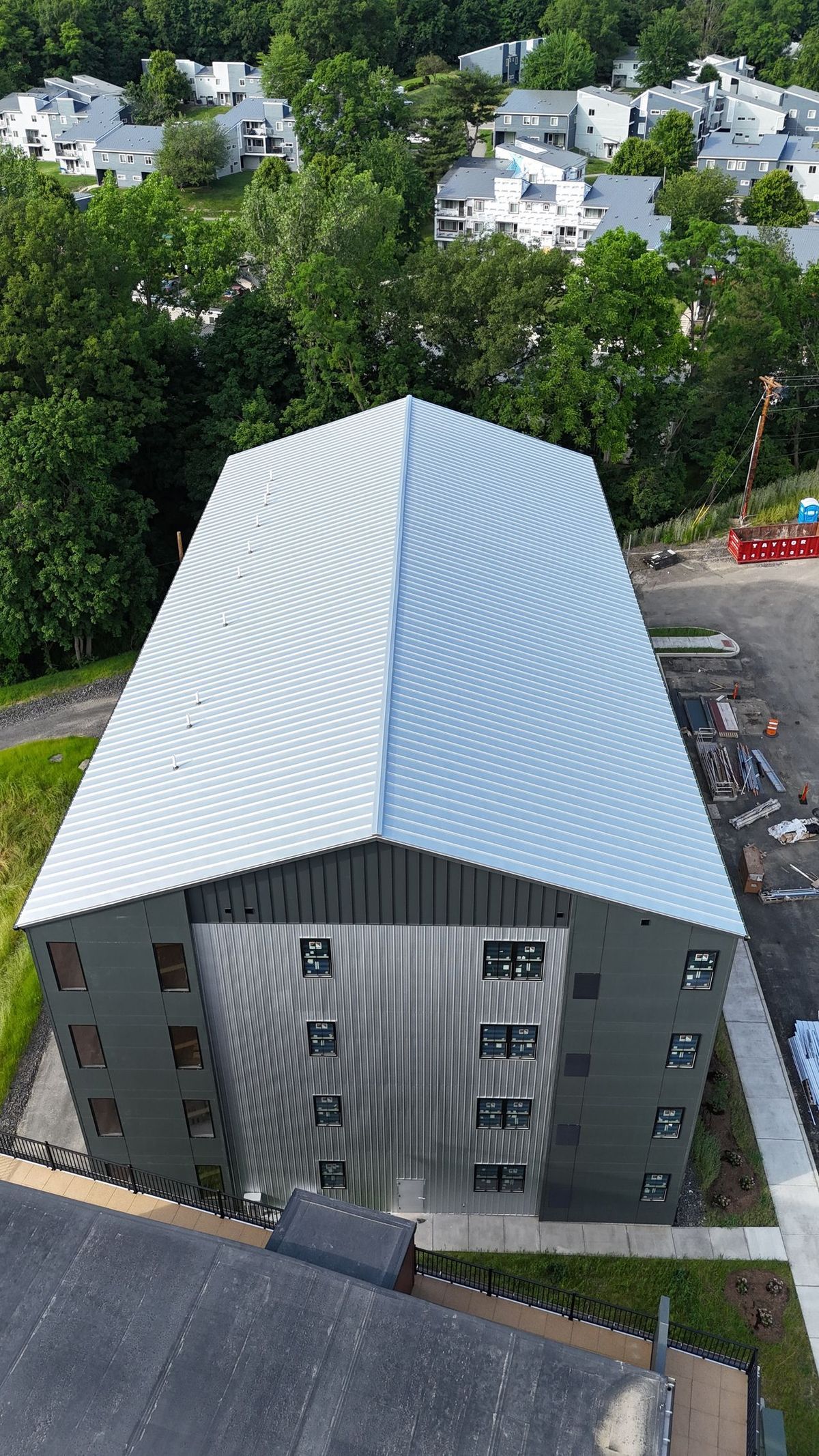An aerial view of a large building with a metal roof surrounded by trees.
