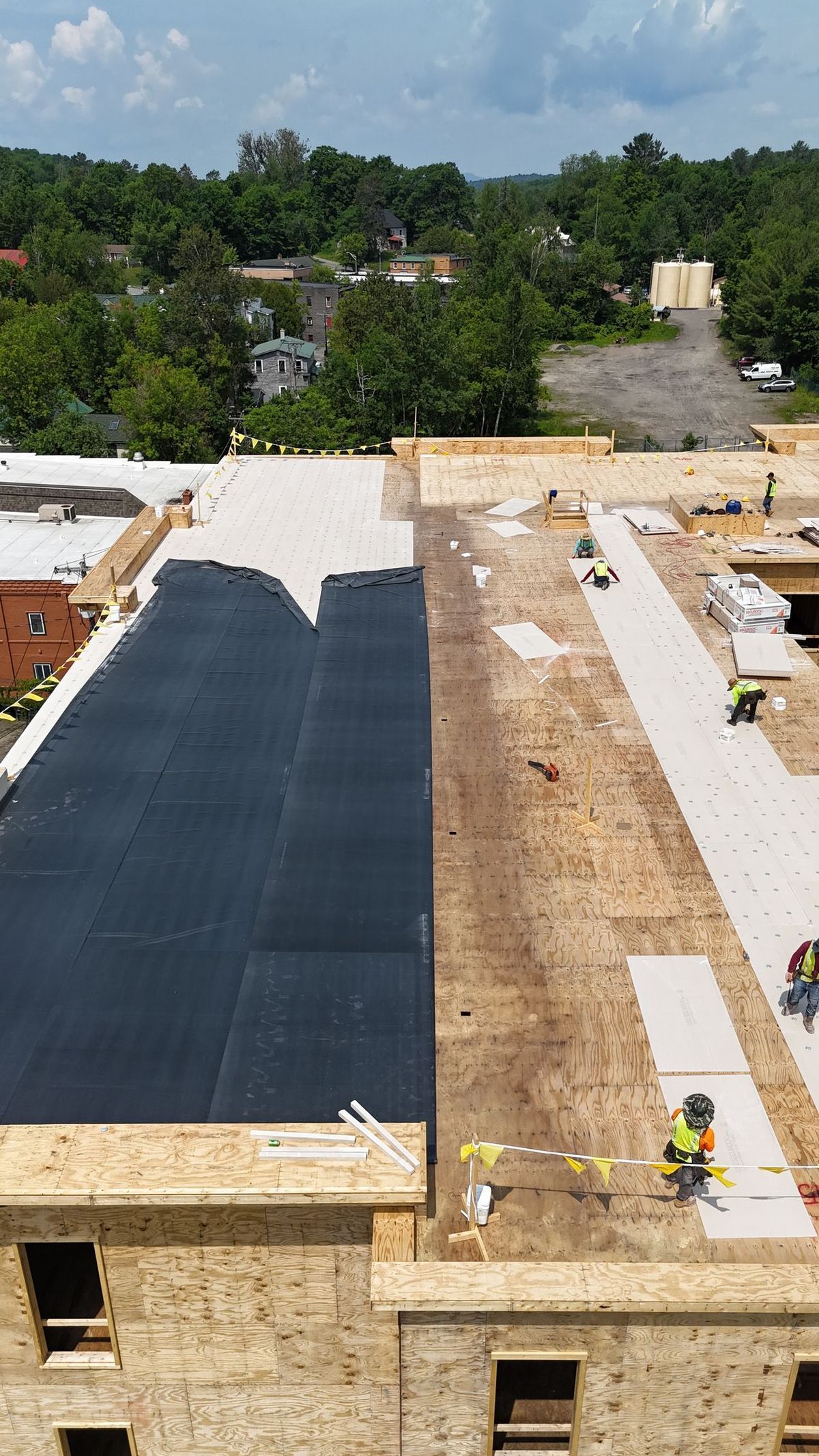 An aerial view of a building under construction with workers on the roof.