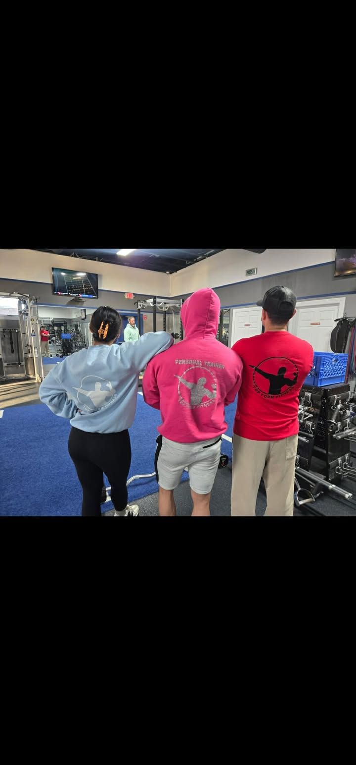 Three people stand with arms around each other in a brightly lit indoor arcade.