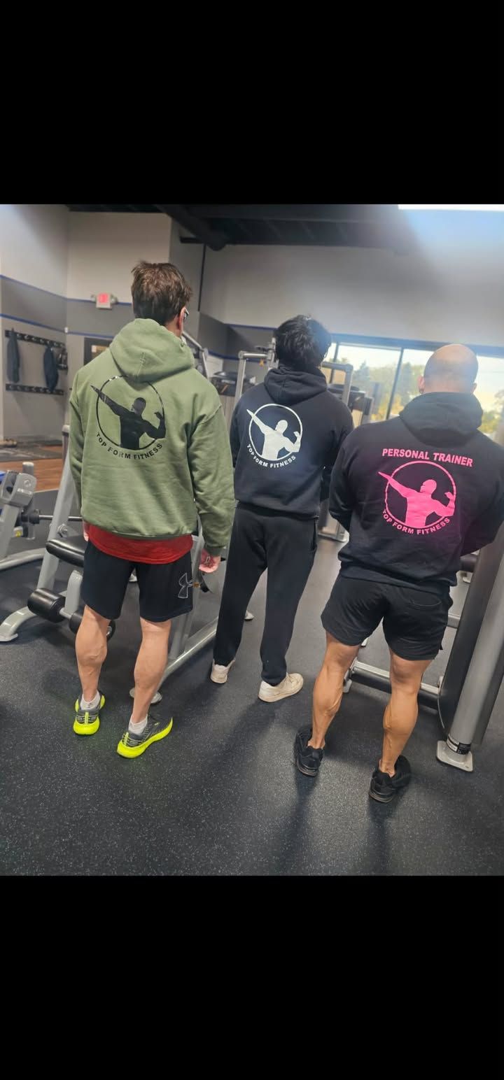 Three people in hoodies and athletic shorts standing in a gym, seen from behind.
