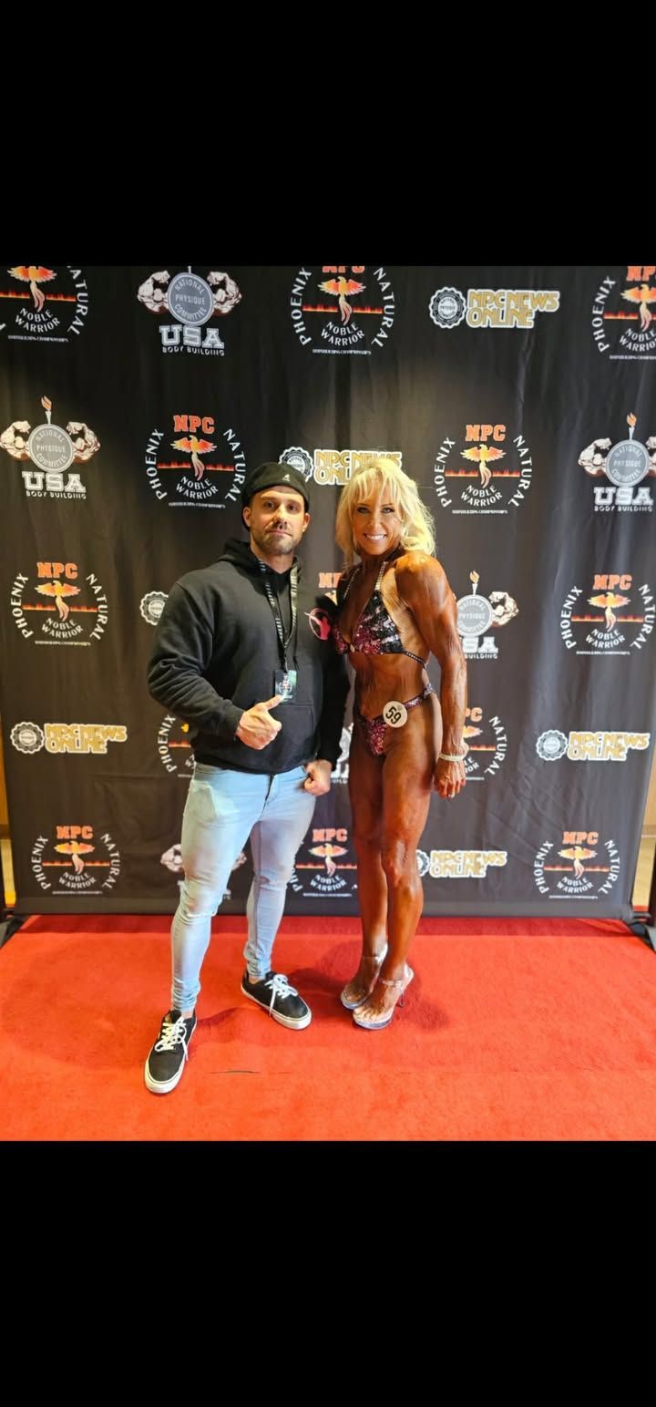 Two people posing on a red carpet in front of a branded step-and-repeat backdrop.