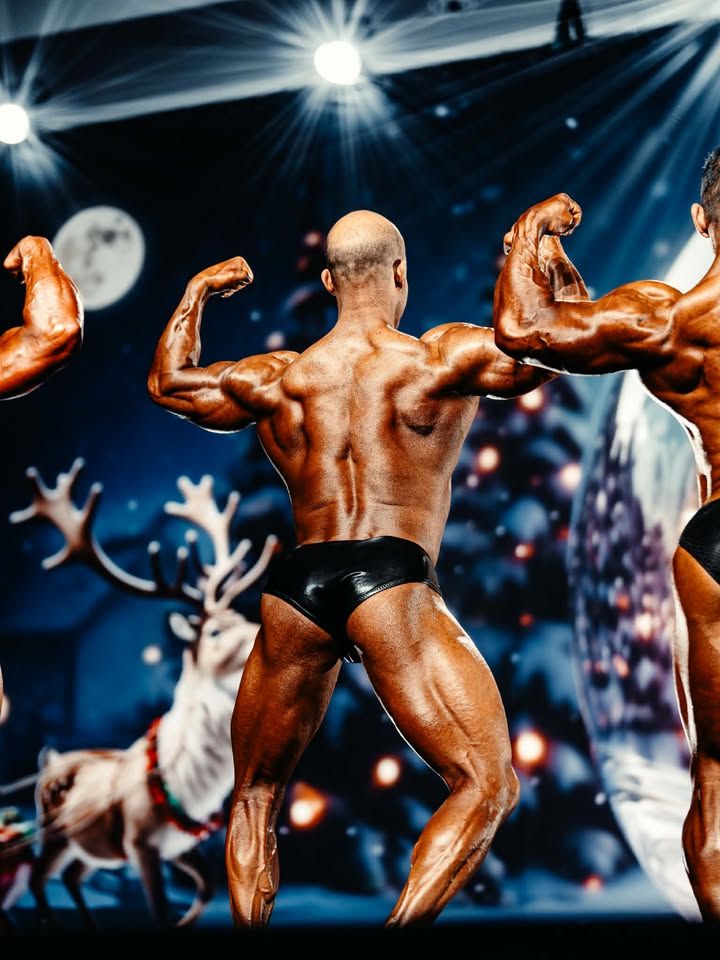 Bodybuilders posing onstage under bright spotlights, with a crowd blurred in the background.