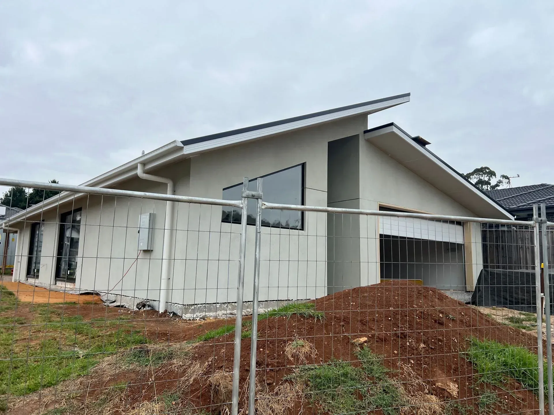 Unfinished modern house with white walls and a sloped roof at a construction site