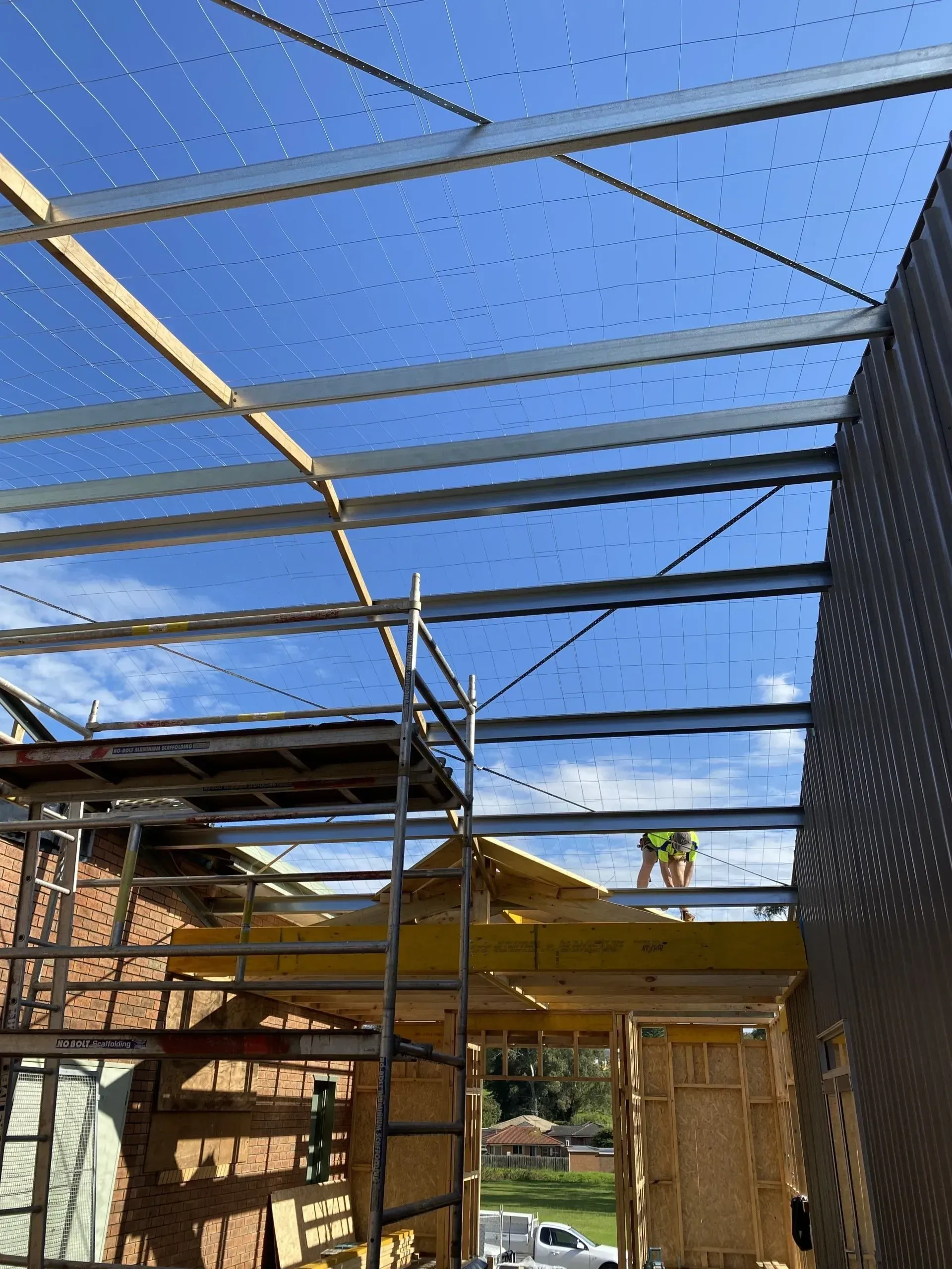 Blue sky seen through a metal roof frame over a building under construction
