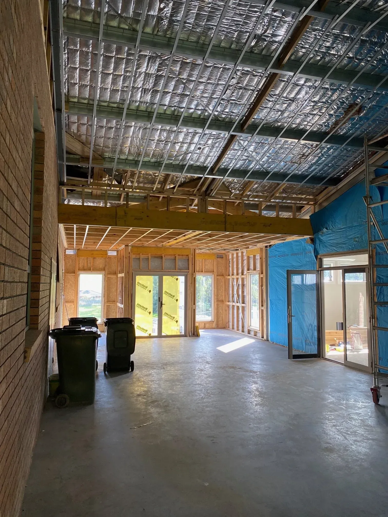 Empty unfinished interior with exposed ceiling, concrete floor, and blue and wood-framed walls