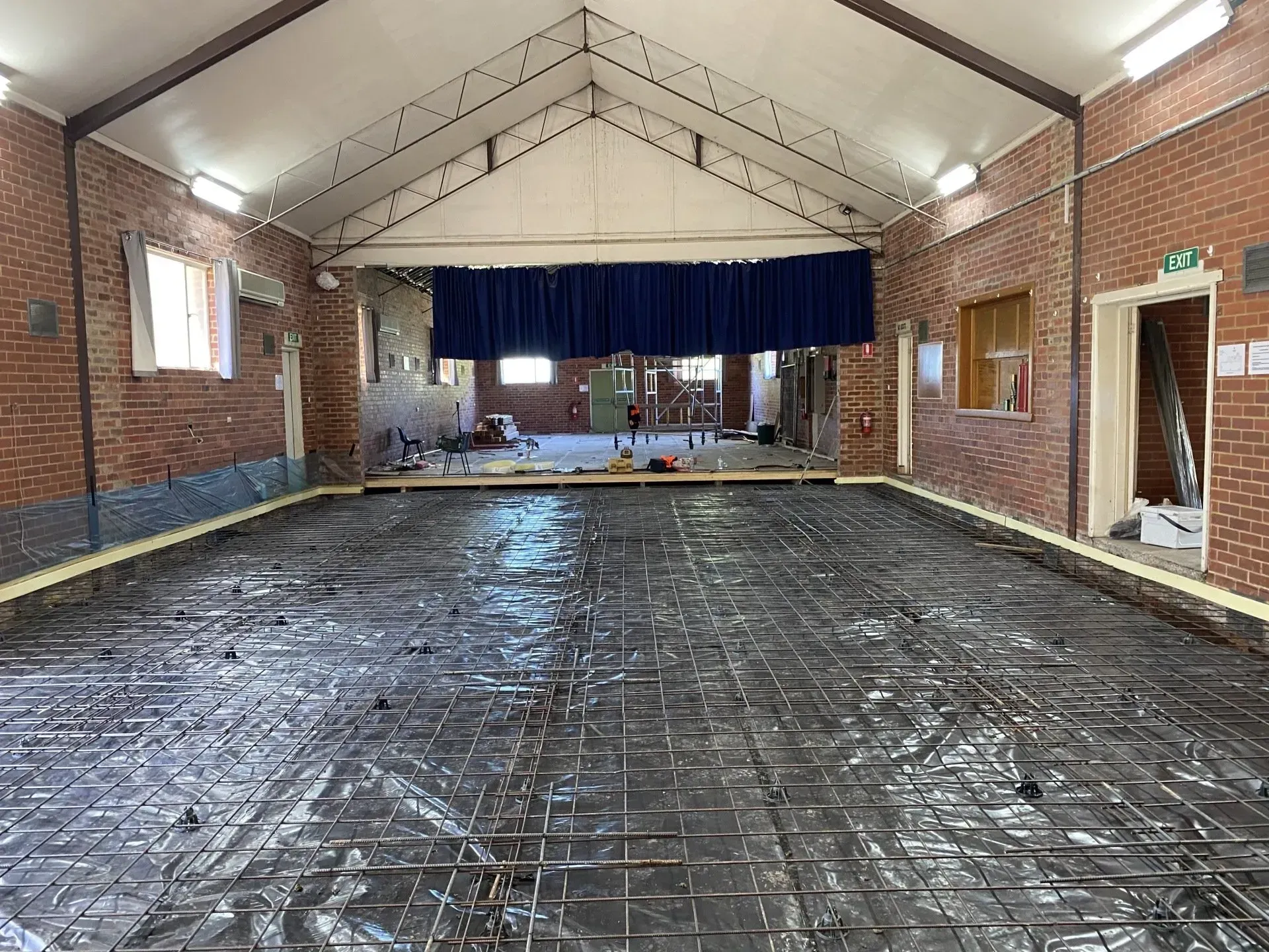 Empty brick hall with a wet concrete floor and stage at the far end