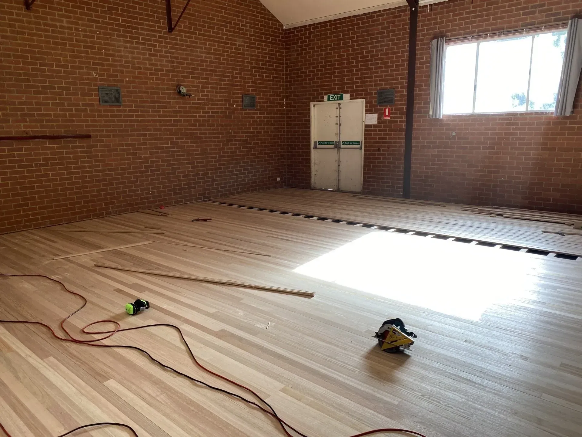 Empty brick room under renovation with floor insulation panels and a bright window light.