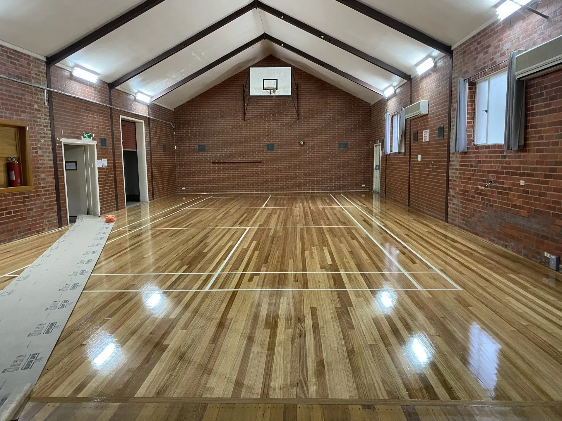 Empty indoor basketball court with polished wooden floor and brick walls