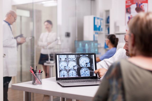 Doctor reviewing brain scans on a laptop in a hospital meeting room