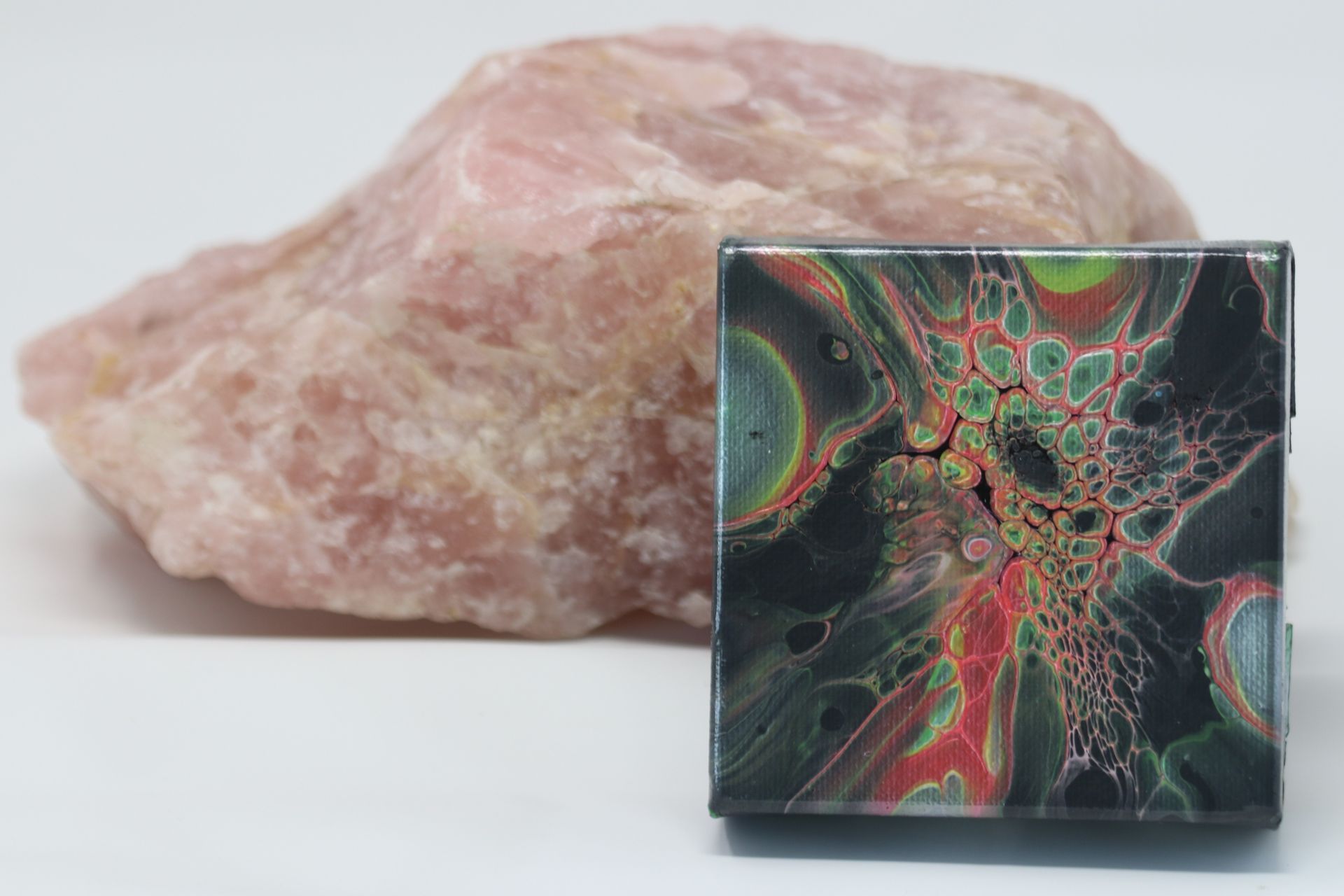 Pink stone behind a black cube with abstract red, green, and orange geometric design