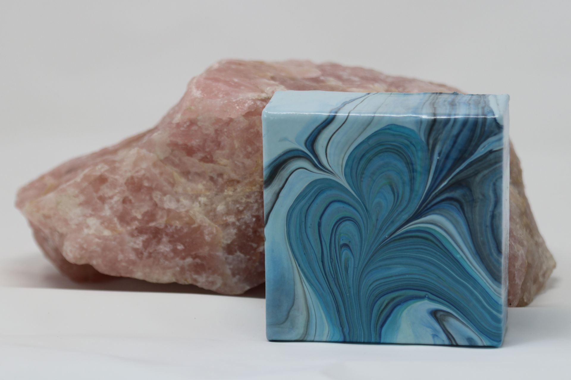 Blue marbled square tile in front of a rough pink stone background