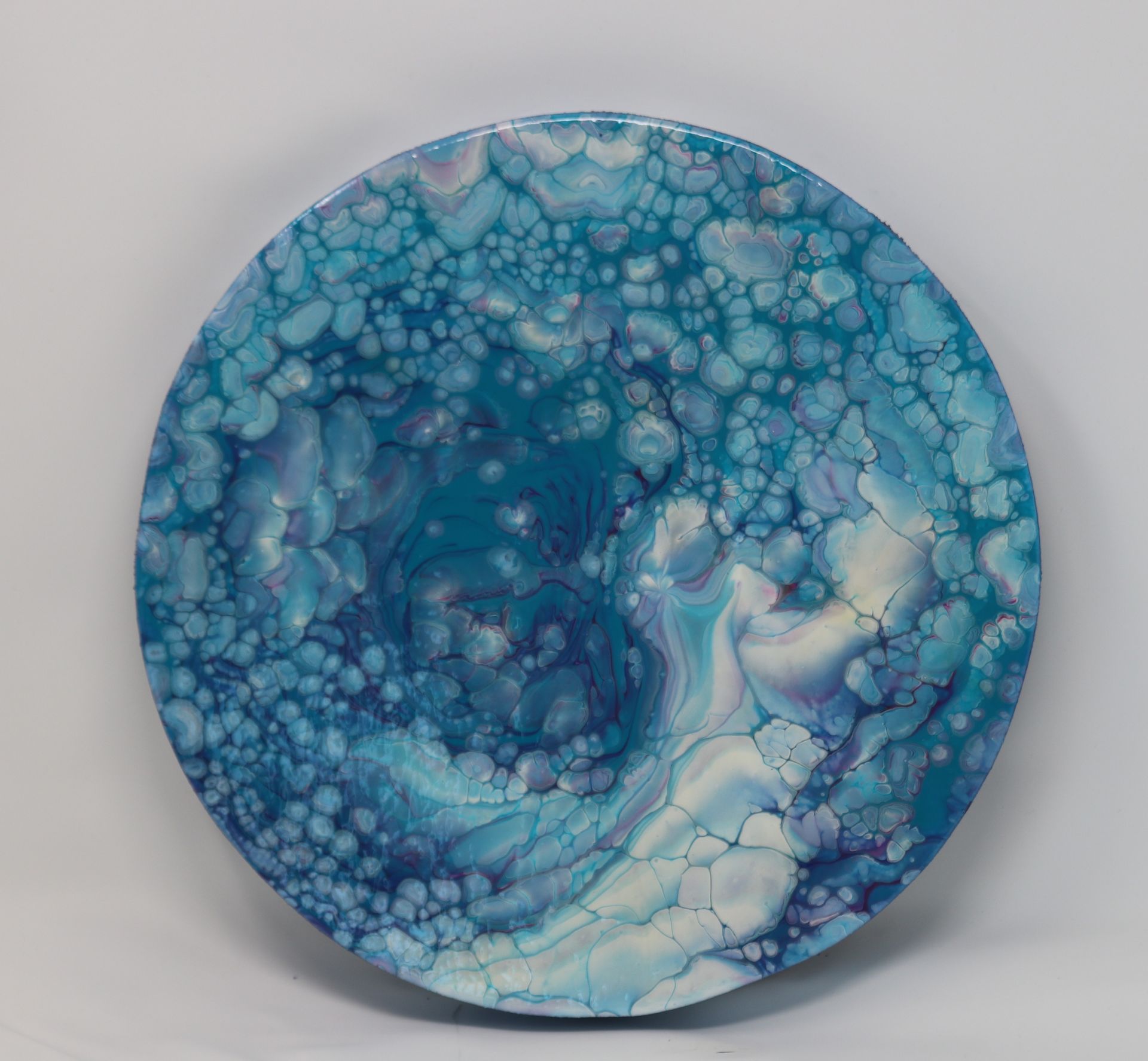 Blue marbled ceramic plate with white and teal swirls on a light background