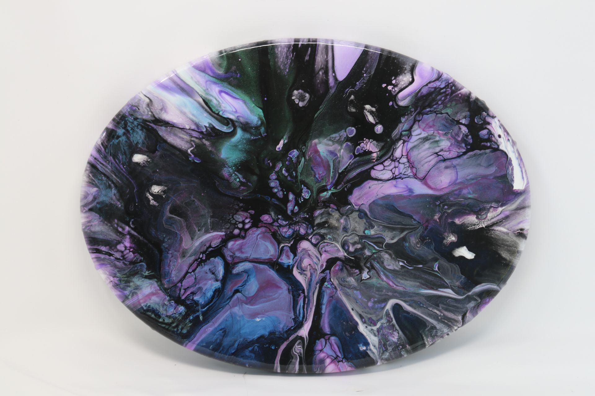 Abstract oval artwork with swirling purple, black, and blue patterns on a white background