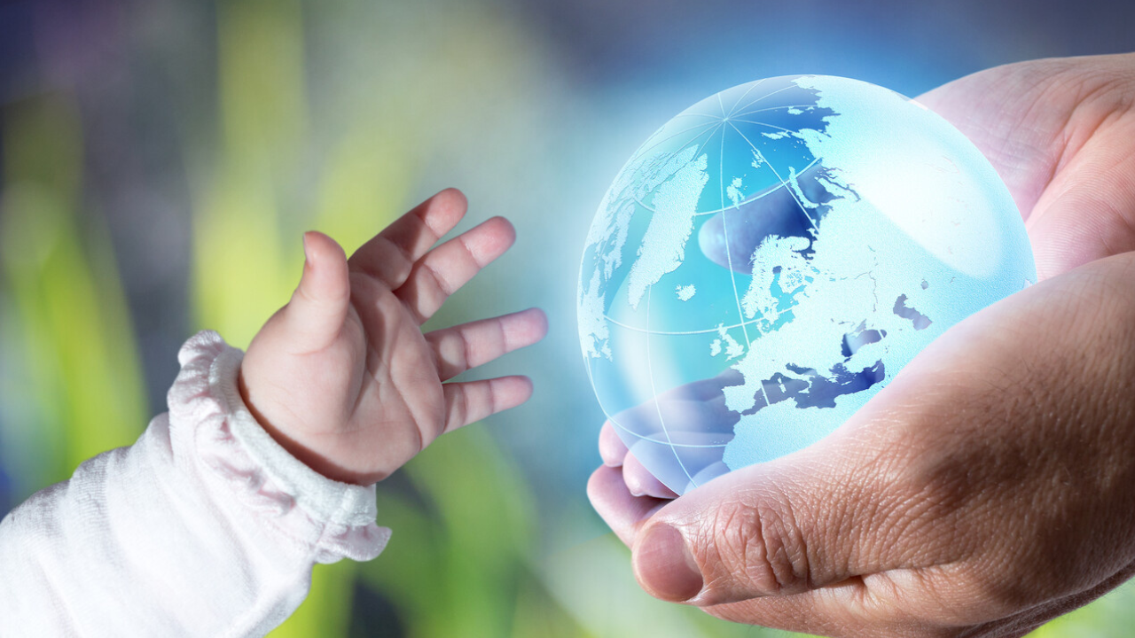 Adult hand holding a glowing globe while a child reaches toward it