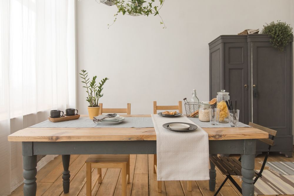 A dining room with a wooden table and chairs and plates on it.
