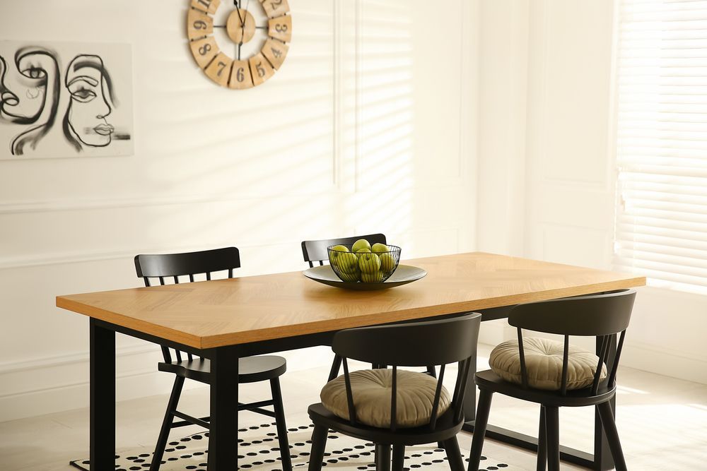 A dining room with a wooden table and chairs and a clock on the wall.
