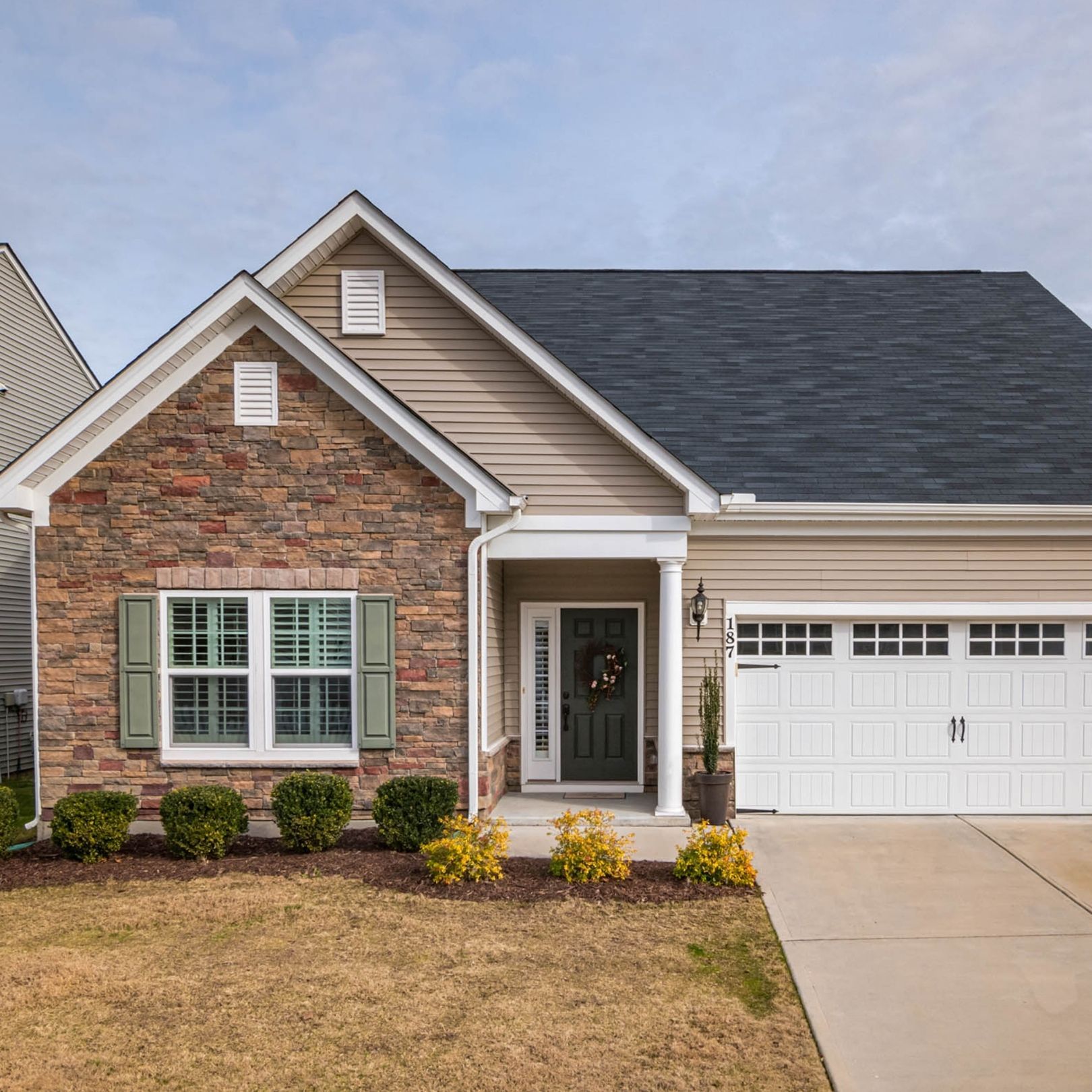 Single-story brick and beige suburban house with a two-car garage and front porch