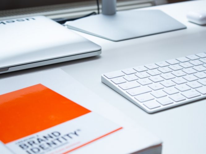 A book titled brand identity sits on a desk next to a keyboard