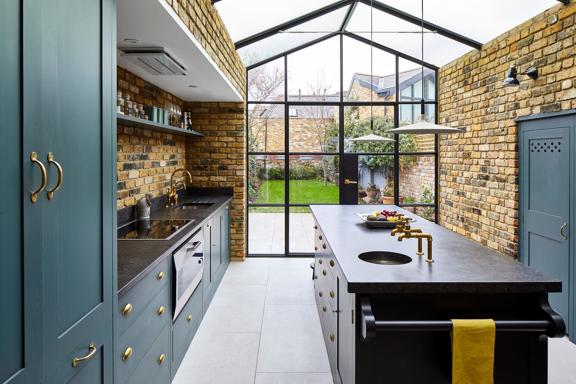 A teal kitchen extension with a brick wall, built by a home alteration contractor.