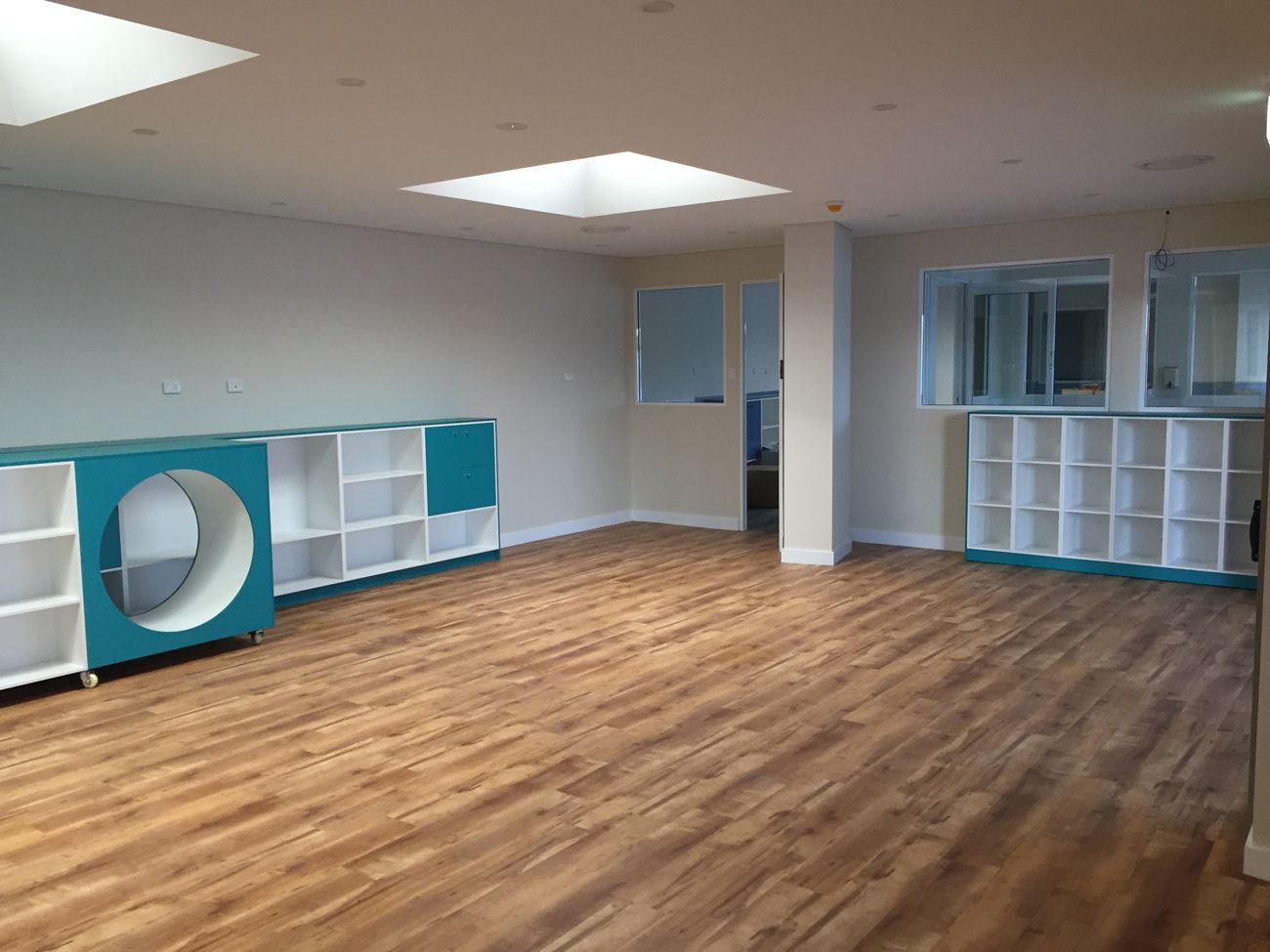 A large empty room with hardwood floors and blue shelves