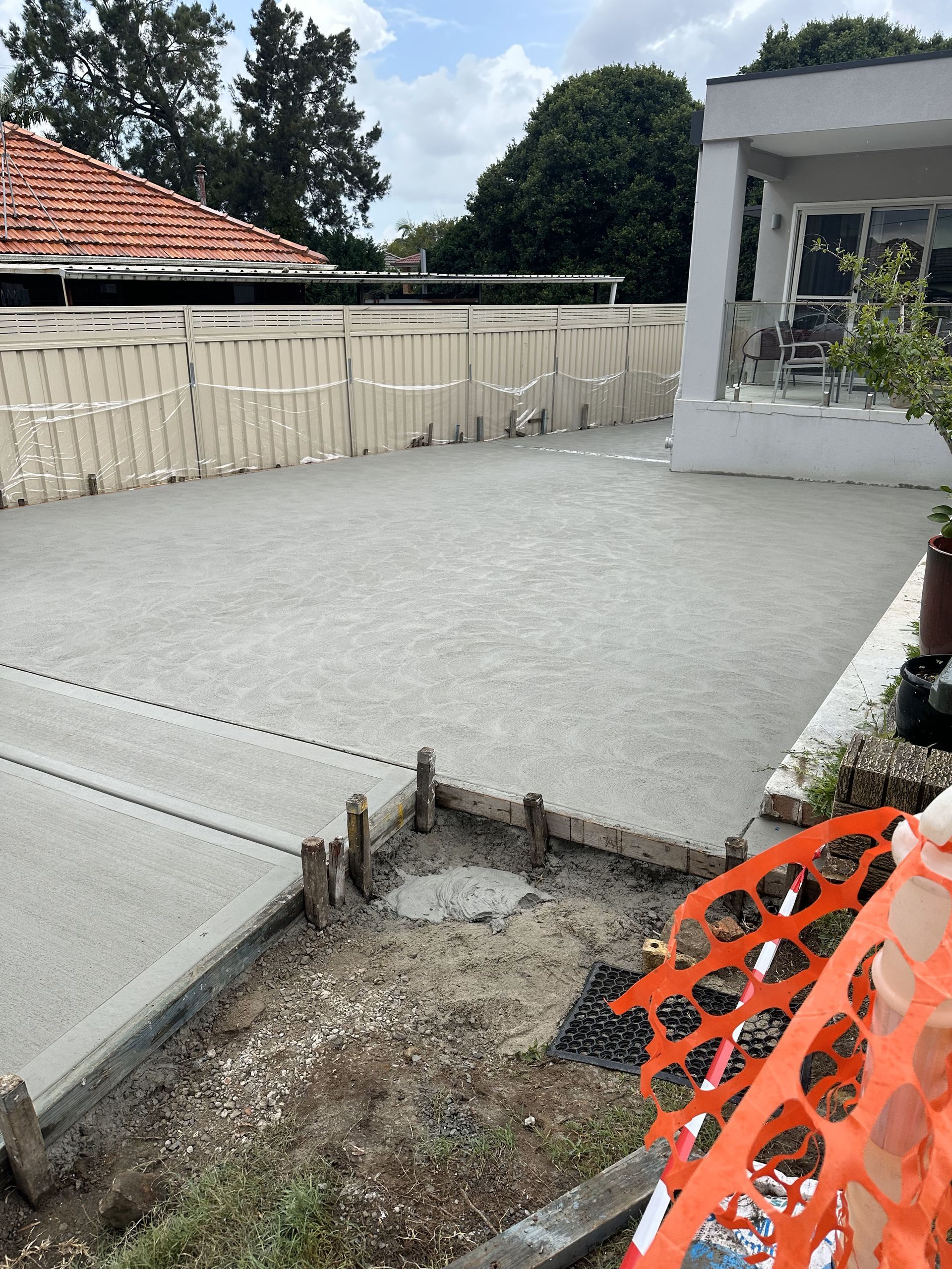 Freshly poured concrete driveway next to a house with a white exterior.