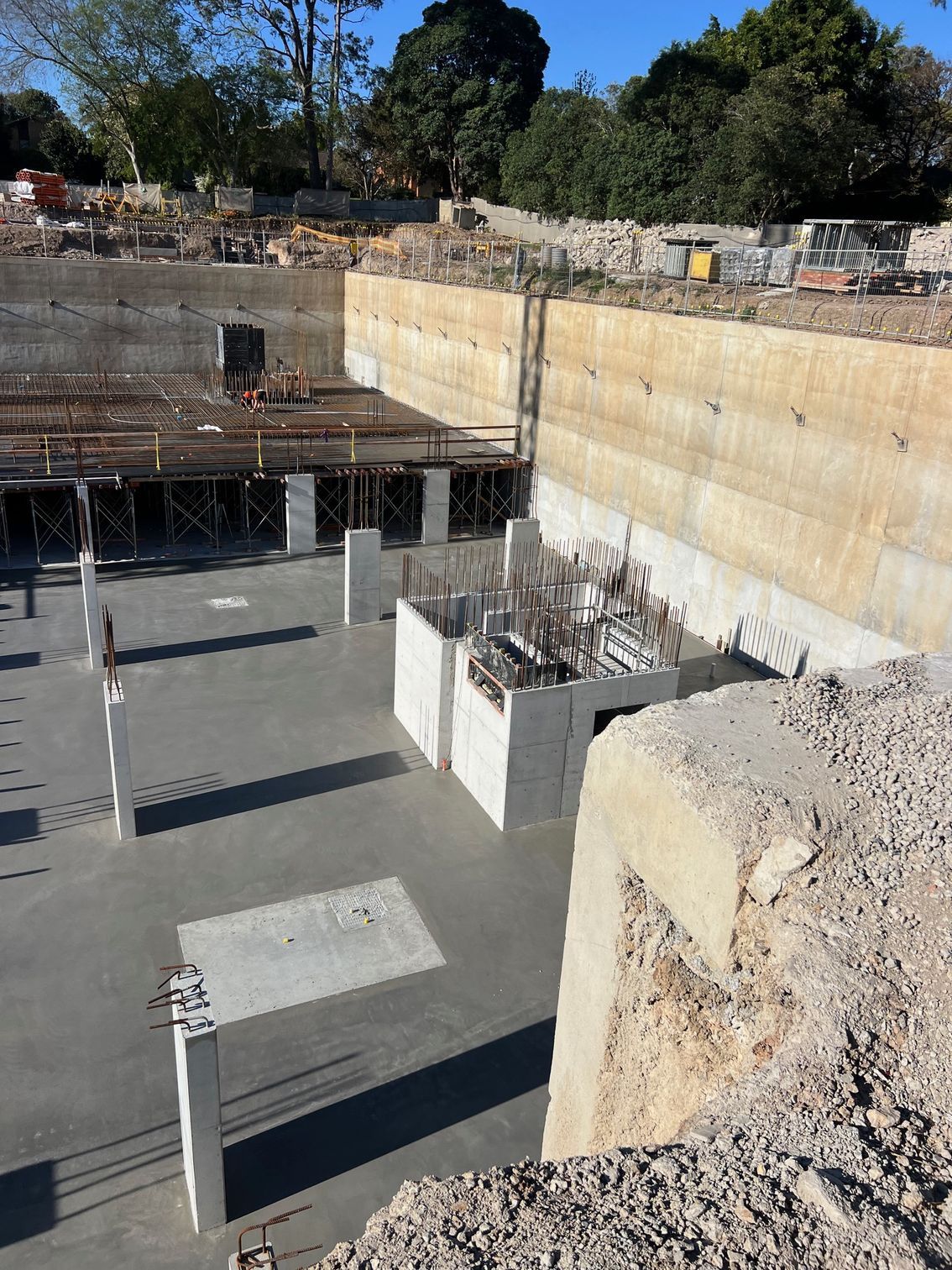 Construction site, concrete foundations, walls, and supports; bright daylight.